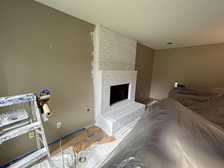 In a Tualatin home, a room with a white brick fireplace is undergoing a paint job.