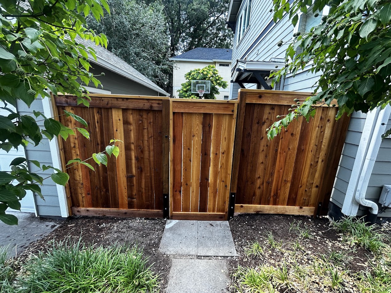 A wooden gate with side panels stands between two houses in Chadderton; Pearl Painters could paint or stain this for you.