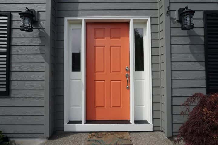 A gray house in Tigard featuring an orange front door.