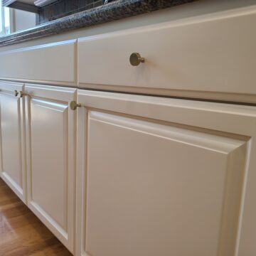 White painted cabinets with silver handles and dark countertop on wood floor, by Pearl Painters, Portland.