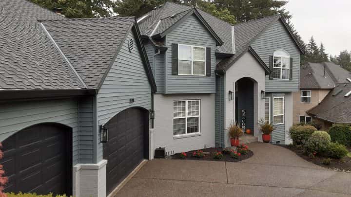A Pearl Painters connected home with gray siding and garage doors.