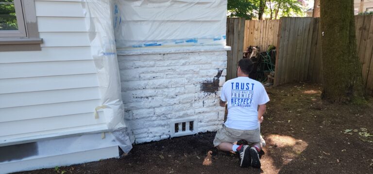 A man painting a house with white paint.