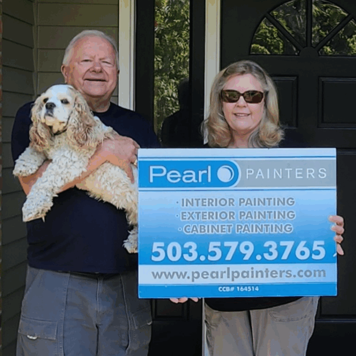 Two people in front of a door, one with a dog, one with a Pearl Painters sign for painting services in Portland.