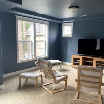 living room with walls painted a medium blue tone filled with a TV and furniture