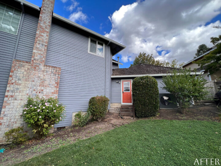 A Beaverton home in the Cooper Mountain Neighborhood with a blue door and bushes in the yard.