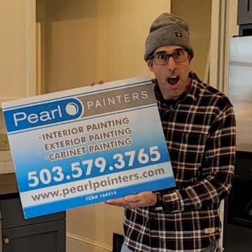 A man holding up a sign that says pearl painters is showcasing their exceptional kitchen makeover skills in Portland. Their remarkable work has even garnered rave reviews on Google.