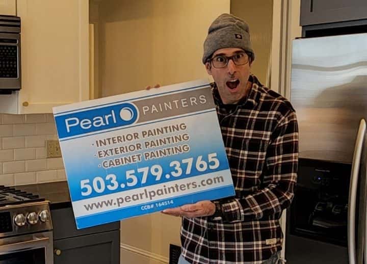 A man holding up a sign that says pearl painters is showcasing their exceptional kitchen makeover skills in Portland. Their remarkable work has even garnered rave reviews on Google.
