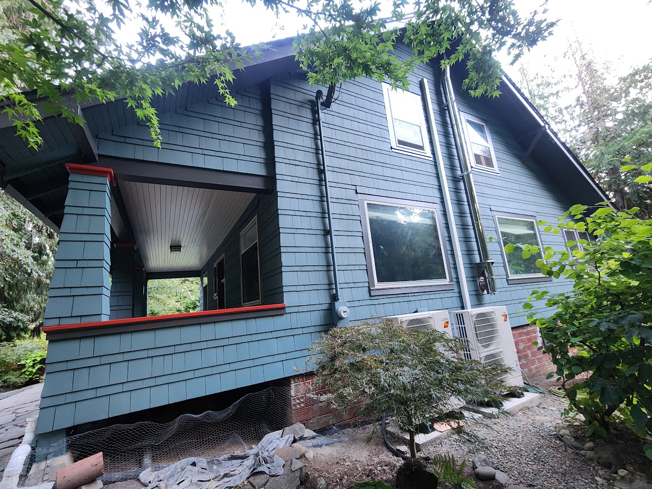 Blue two-story Gentry house with red trim and windows, painted by Pearl Painters in Portland, greenery and AC unit outside.
