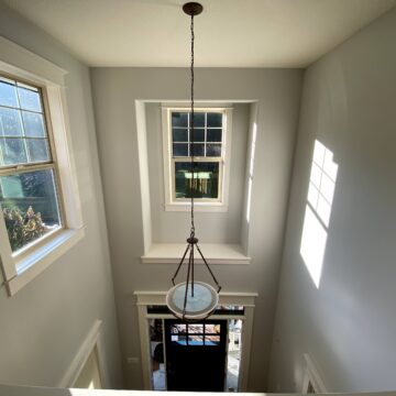 A bright and lightened hallway with windows and a fun light fixture.