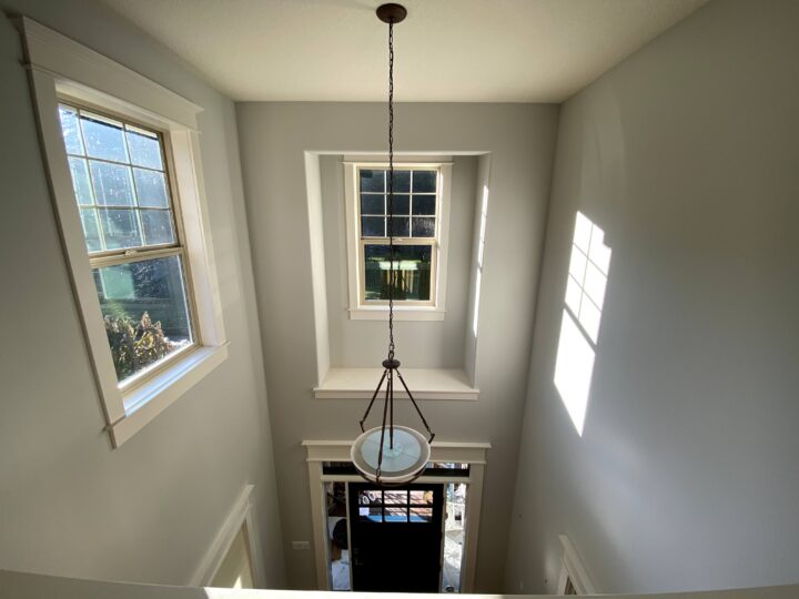 A bright and lightened hallway with windows and a fun light fixture.