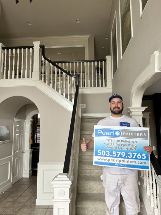 Pearl Painters sign held in front of interior painting job - staircase, walls, wainscoting, trim