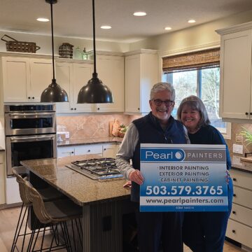 happy couple holds Pearl Painters sign after cabinets repainted