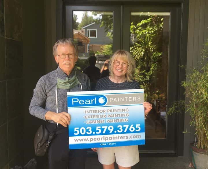 A couple in Lake Oswego standing in front of their home holding a Re-Paint sign.