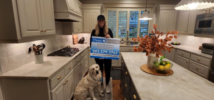 satisfied customer holds Pearl Painters sign in kitchen after cabinet painting