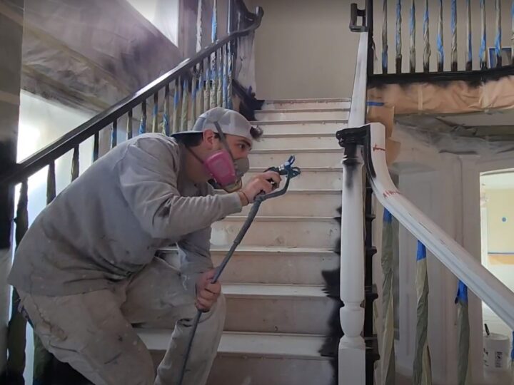 A painter using a paint sprayer to paint a staircase.