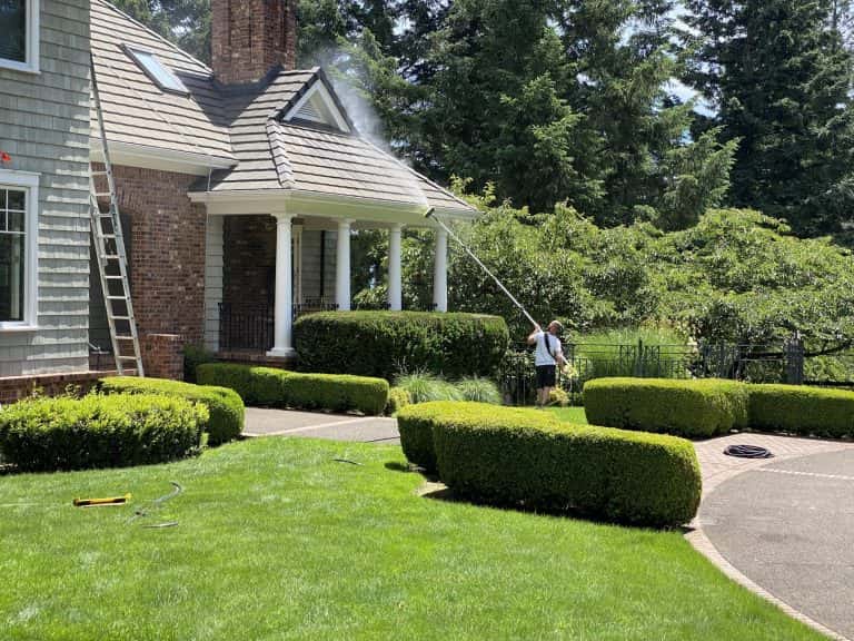 A man in Oregon City is re-painting a house with a pressure washer.
