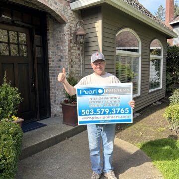 A man holding up a sign in front of a Lake Oswego house.
