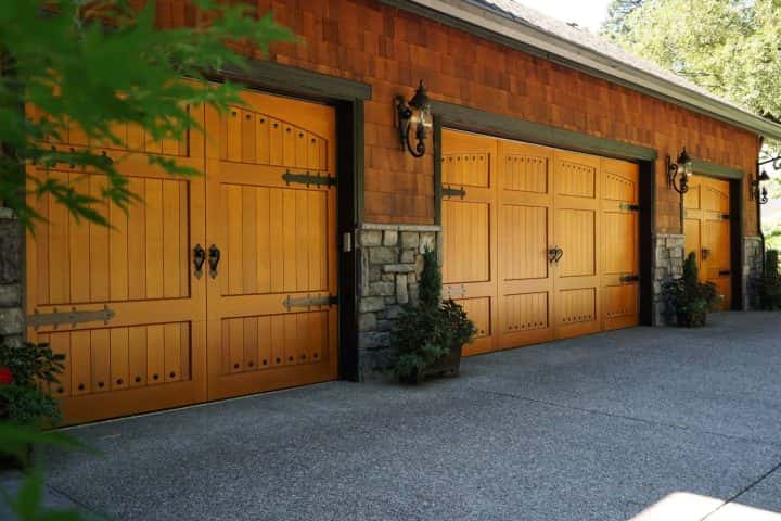 A house with wooden garage doors and a stone wall.