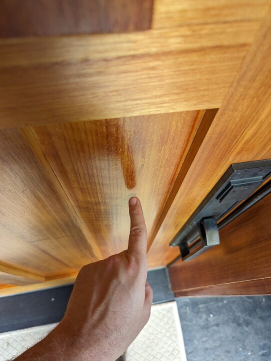 Finger pointing at a blemish on a wooden front door for Pearl Painters in Portland.