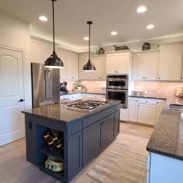 A kitchen with granite counter tops and stainless steel appliances, perfect for cabinet painting.
