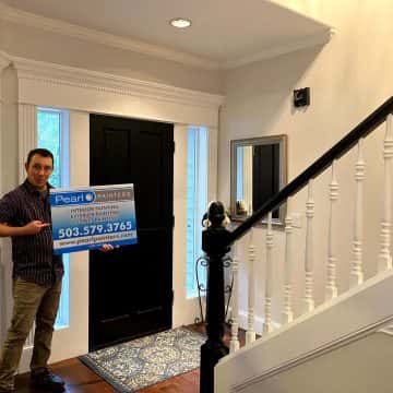 A man standing in front of a door holding a sign for interior painters.