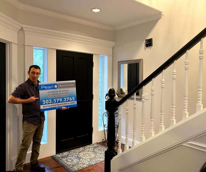 A man standing in front of a door holding a sign for interior painters.