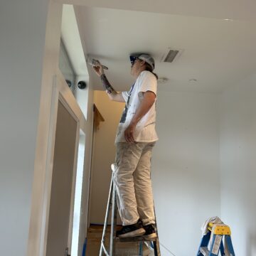 A thoughtful man working on a townhouse painting project, aiming for a 5-star Google Review.