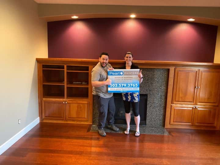 Two people standing in front of a fireplace holding a check.