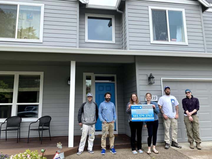 Happy clients hold a sign that says Pearl Painters with business information outside their home in Portland