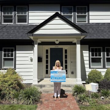 Woman on brick walkway in front of white house displays Pearl Painters sign—exterior painting, Portland, 503-579-3765.