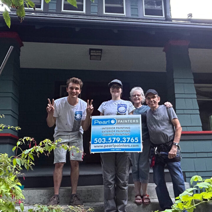 Four people stand in front of a house in Portland, two holding a Pearl Painters painting sign. All are smiling.