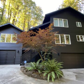 Modern house in Portland with black siding, dark paint, large windows, two garages; painted by Pearl Painters.