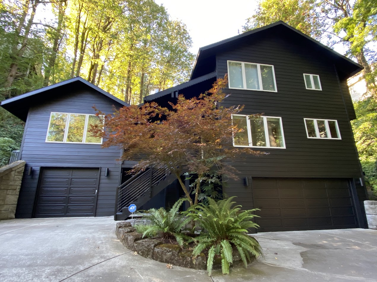 Modern house in Portland with black siding, dark paint, large windows, two garages; painted by Pearl Painters.