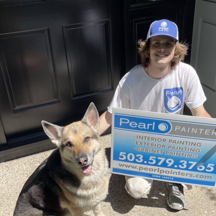 Pearl Painters painter kneels by German Shepherd, holding a Pearl Painters sign for painting services in Portland.