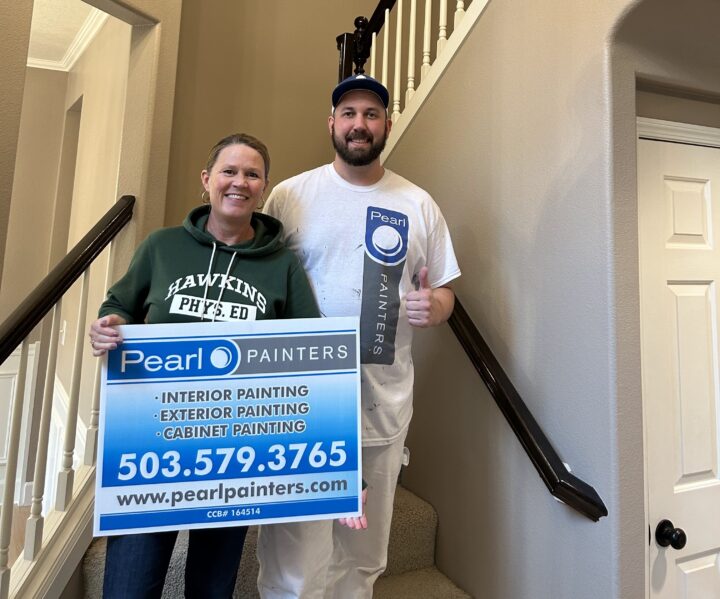 Two painters stand on stairs in Portland, one in a hoodie, one in painting gear, holding a Pearl Painters sign with contact info.