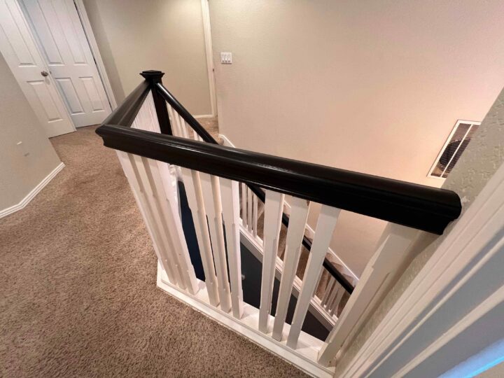 A carpeted staircase with a Bull Mountain Handrail and white balusters is shown, leading down to a lower floor. A hallway with closed doors is visible on the upper floor, offering a market-ready modern look.