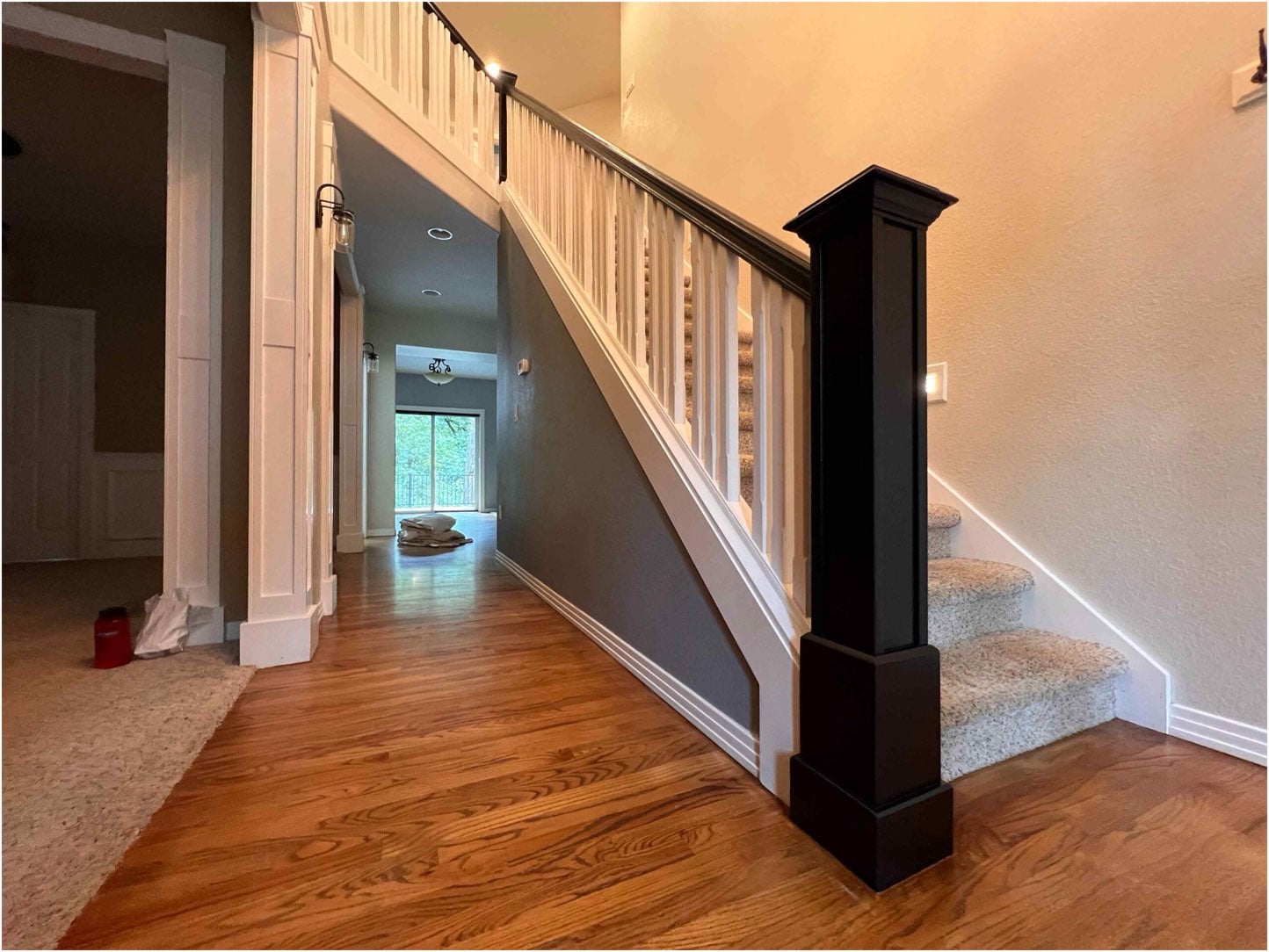 A staircase with wooden steps and a Bull Mountain Handrail is shown, leading to an upper level. The surrounding area, designed for a modern look, features wood and carpet flooring, creating a market-ready appeal.