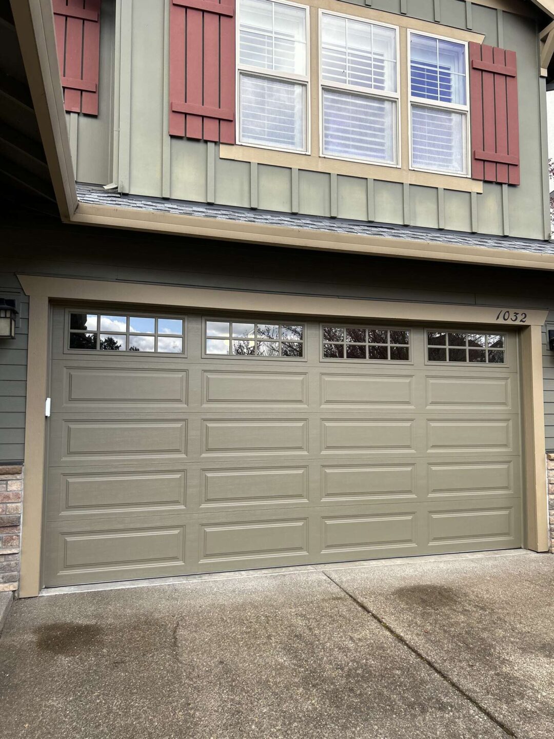 A painter from Pearl Painters painted a green garage door with rectangular panels and upper windows at 1032 Taylor’s house in Portland, which has red shutters and horizontal siding. This painting was done in April 2025.