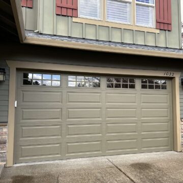 A painter from Pearl Painters painted a green garage door with rectangular panels and upper windows at 1032 Taylor’s house in Portland, which has red shutters and horizontal siding. This painting was done in April 2025.