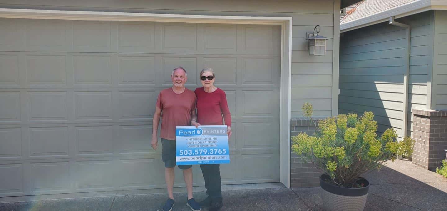 Two people standing in front of a Tigard garage with a sign.
