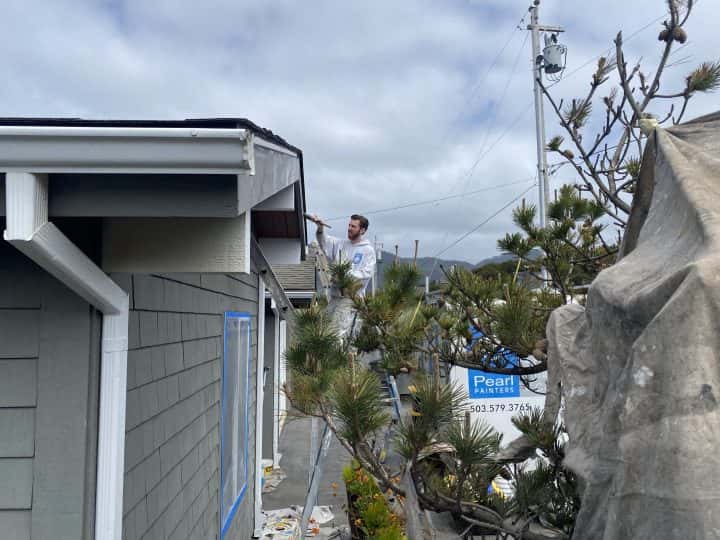 A man is painting the exterior of the Manzanita Beach House in 2022.