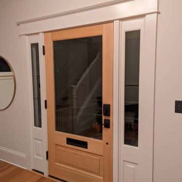 A front door sealed to protect against inclement weather welcomes visitors into an entryway adorned with a stylish rug, creating a warm and inviting space in Portland.