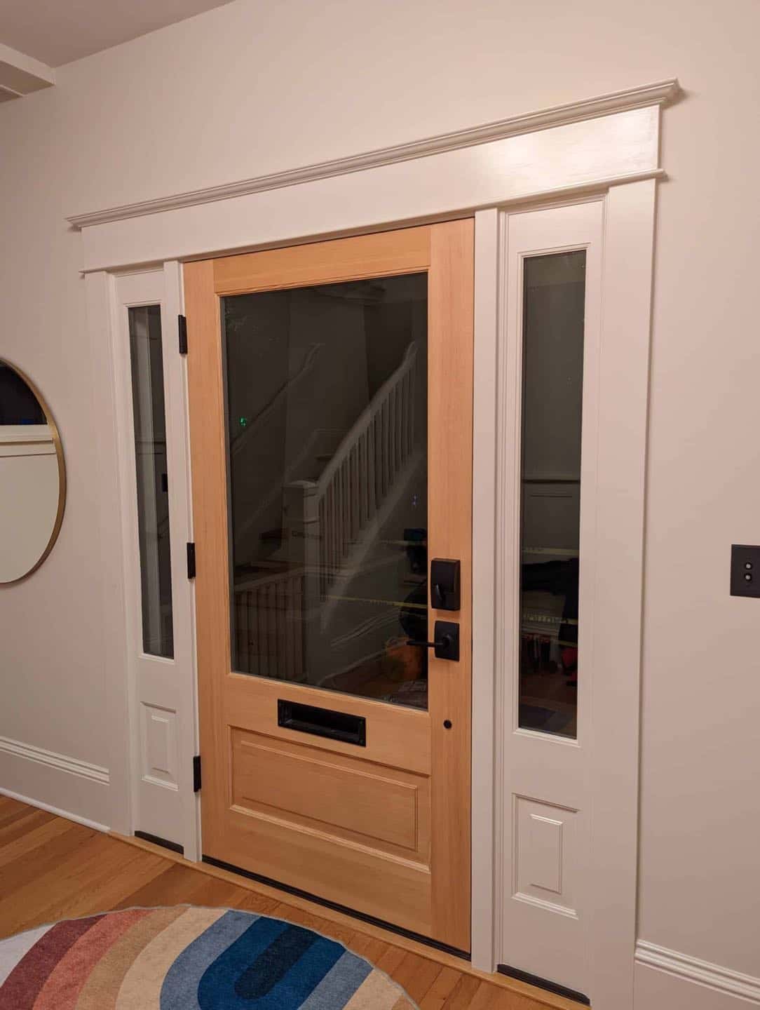 A front door sealed to protect against inclement weather welcomes visitors into an entryway adorned with a stylish rug, creating a warm and inviting space in Portland.