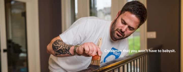 A man painting a wooden railing with a brush.