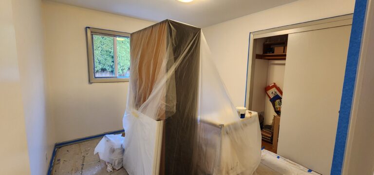 A room in the home is being painted with plastic covering the furniture.