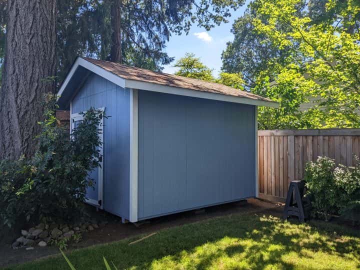 A homeowner's blue shed in Tigard, as seen in a Google review surrounded by trees.