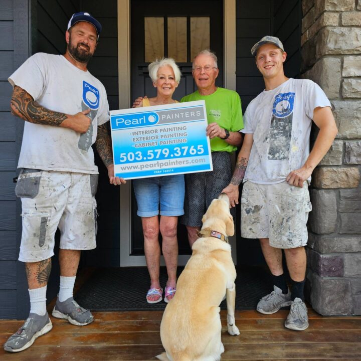 Two painters and an older couple on a porch in Portland hold a Pearl Painters sign; a yellow lab sits in front.