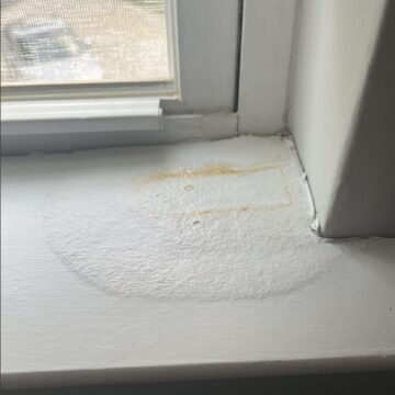 A window sill with visible water damage and discoloration near the corner.