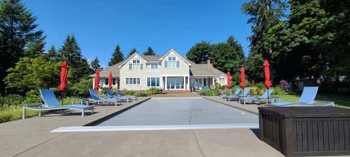 A pool with lounge chairs and umbrellas in front of a house in Oregon City.