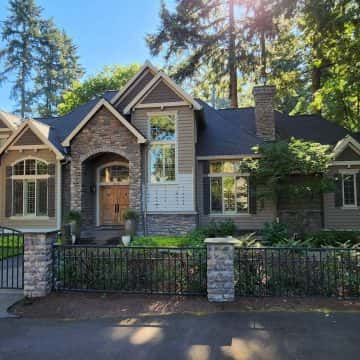 A Lake Oswego home with a fence and trees in front of it.